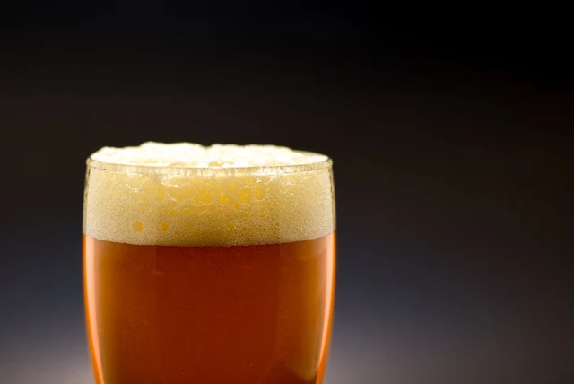 Magners vs Strongbow compared, shown by a glass of golden apple cider