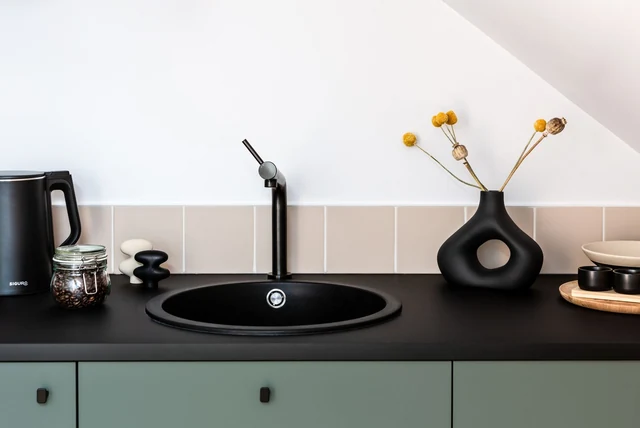 Matt black kitchen taps UK shown with a black sink and pale units